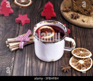 Vin brulé in un ferro bianco mug su un marrone tavolo in legno Foto Stock