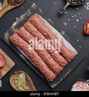 Salsicce crude al kebab di lula su tavola e spezie, vista dall'alto Foto Stock