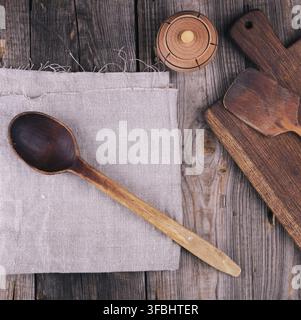 vecchio cucchiaio vuoto in legno e tagliere rettangolare, vista dall'alto, sfondo grigio in legno Foto Stock