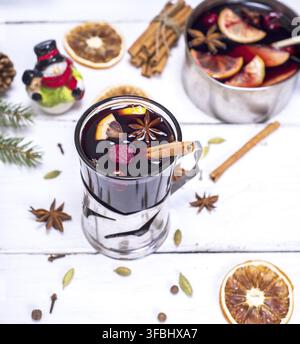 Vin brulé in un bicchiere con un ferro da stiro portabicchieri su un bianco sullo sfondo di legno, vista dall'alto Foto Stock