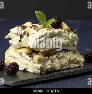 Dessert Pavlova di proteine cotte montate su una tavola nera decorata con foglie di menta, primo piano Foto Stock