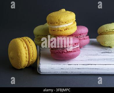 Multicolore di dolci da forno di farina di mandorle macarons su un di legno bianco, scheda Sfondo nero Foto Stock