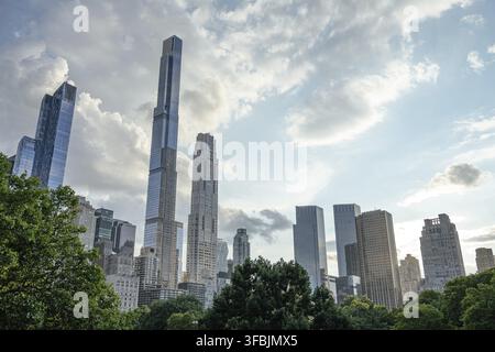 Alti grattacieli dominano lo skyline di Midtown Manhattan, innalzandosi sopra gli alberi di Central Park. Gli edifici in vetro riflettono la luce del giorno sotto un d Foto Stock