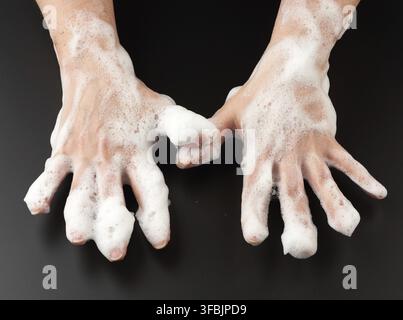 mani femminili in cialde bianche su sfondo nero, concetto di lavaggio delle mani contro i batteri, cura del corpo, vista dall'alto Foto Stock