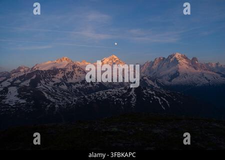 La luna piena sopra la catena del Monte Bianco al tramonto nelle Alpi francesi. Foto Stock