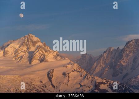 La luna piena sopra la catena del Monte Bianco al tramonto nelle Alpi francesi. Foto Stock