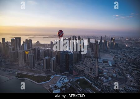 I palloni ad aria calda fluttuano sopra lo skyline di Doha all'alba Foto Stock