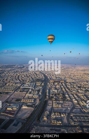 Mongolfiere volano su una città estesa all'alba Foto Stock