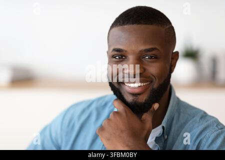 Ritratto closeup di bella sorridente afroamericana che tocca la barba Foto Stock
