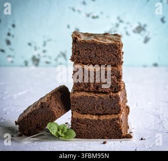 Pila di strati quadrati di cotto torta brownie su una superficie bianca Foto Stock