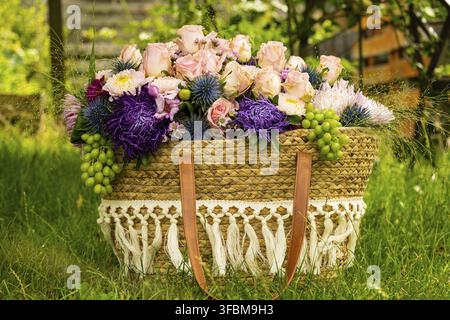 Bellissimo arrangiamento floreale colorato con rose e altri fiori in un cesto Foto Stock