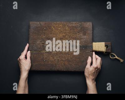 Tagliere in legno vuoto a mano femmina su tavola in legno nero, vista dall'alto Foto Stock
