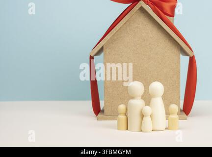casa di legno e figure famiglia in miniatura, ipoteca e concetto di prestito, primo piano Foto Stock