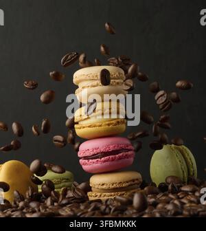 Pila di macaron colorati e chicchi di caffè volanti su sfondo nero Foto Stock
