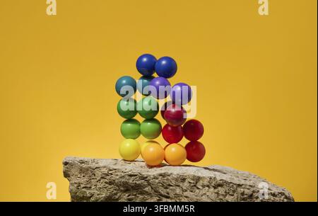 Sfondo astratto con palline di plastica multicolore su sfondo giallo, palcoscenico per la dimostrazione di cosmetici e prodotti Foto Stock