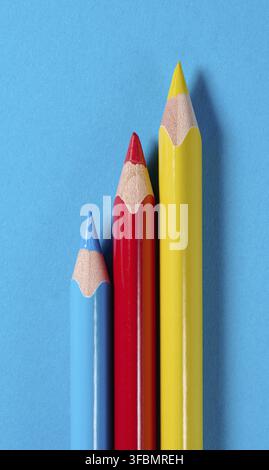 Tre matite di legno colorate su sfondo blu Foto Stock