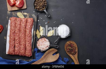 Salsicce crude al kebab di lula su tavola e spezie, vista dall'alto Foto Stock