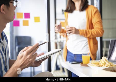 gruppo di uomini d'affari che parlano di progetto e preparare la pizza e patatine fritte per il pranzo in azienda insieme in ufficio Foto Stock