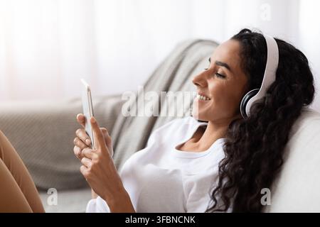 Felice giovane donna in cuffia con telefono cellulare Foto Stock