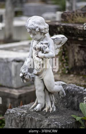 Patzcuaro, Michoacan, Messico - 27 ottobre 2021: Vista di una statua di angelo in pietra consumata che tiene fiori in un cimitero, riflettendo l'atmosfera solenne Foto Stock
