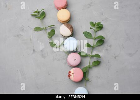 Macaron al forno con sapori diversi su sfondo grigio cemento, vista dall'alto Foto Stock