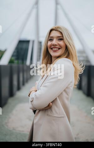 Donna d'affari sicura di sé che sorride su un ponte urbano con un blazer leggero, ritratto professionale all'aperto Foto Stock