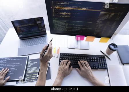 Programmatore pensieroso che lavora su un PC desktop a tecnologie di codice di programmazione o alla progettazione di siti web in un'azienda di sviluppo software Foto Stock