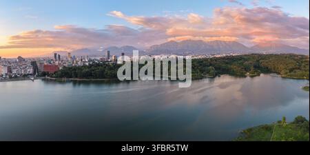 Panorama aereo ad alta risoluzione che mostra lo skyline urbano di Tirana tra il Lago Artificiale, il Grande Parco e le montagne circostanti sotto una vista drammatica Foto Stock