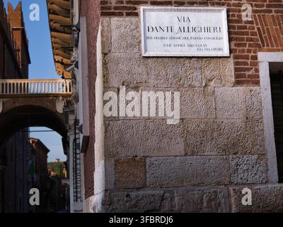 Insegna storica della strada Via Dante Alighieri su una facciata in pietra e mattoni nel centro storico di Verona, Italia, vicino a Piazza dei Signori. Foto Stock