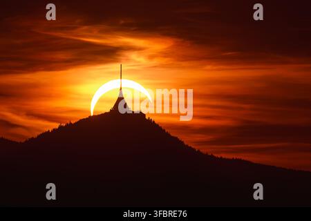 Un'eclissi solare parziale crea un croissant luminoso dietro la Torre Jested sul Monte Jested al tramonto vicino a Liberec, Repubblica Ceca Foto Stock