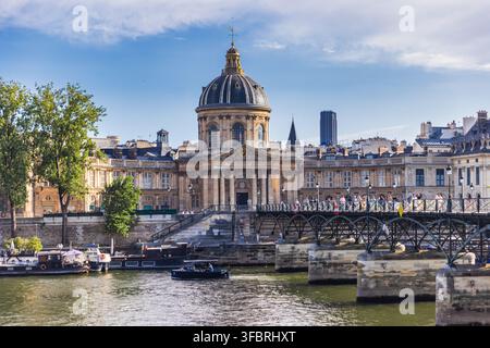 PARIGI, FRANCIA - 20 LUGLIO 2026: Turisti attraversano il ponte pedonale Pont des Arts sopra la Senna verso l'Institut de France a Parigi. Foto Stock