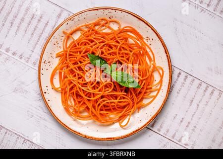Pasta senza glutine - spaghetti di lenticchie. Spaghetti serviti su un piatto con foglie di basilico. Foto Stock