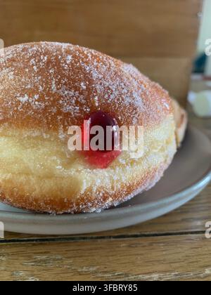Un ciambellone fresco alla marmellata ricoperto di zucchero semolato con ripieno di gelatina di fragole che cola Foto Stock