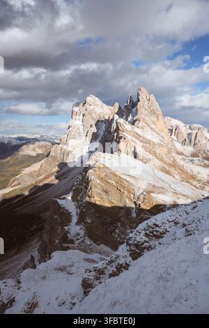 I picchi innevati del Seceda si ergono sopra il terreno alpino frastagliato delle Dolomiti. Paesaggio montano drammatico con nevicata fresca e scogliere di calcare Foto Stock