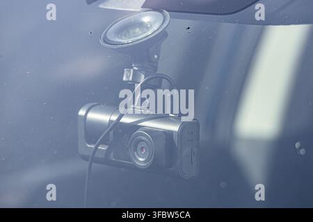 Una moderna telecamera da cruscotto nera montata sul parabrezza di un'auto con una ventosa per la sicurezza del veicolo e la registrazione degli incidenti. Foto Stock