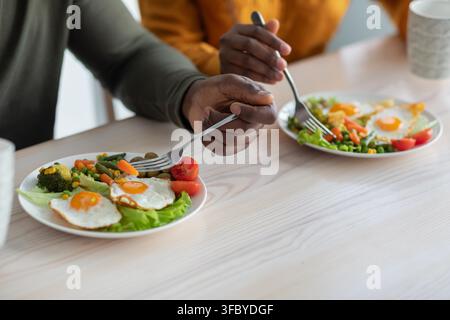 Coppia che gode di una colazione sana insieme, uomo e donna neri che mangiano un pasto fresco in cucina Foto Stock