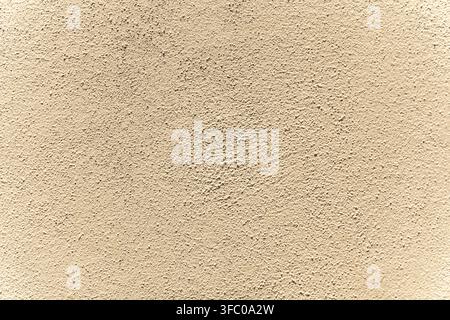 DidascaliaUna vista a tutto schermo di un muro di intonaco ruvido e beige con dettagli superficiali granulari uniformi Foto Stock