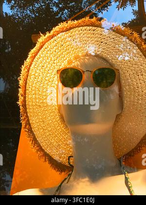 Manichino in una vetrina che indossa occhiali da sole e un cappello di paglia. Foto Stock