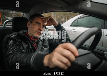 Uomo maturo che vive stress, mal di testa e frustrazione in una decappottabile. mal di testa mentre guida. L'uomo d'affari è stanco di lavorare e sta Foto Stock