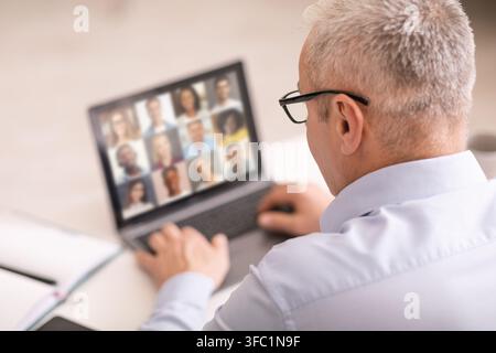 Indietro Vista di uomo d'affari senior che ha una conferenza Web con i suoi dipendenti, Collage Foto Stock