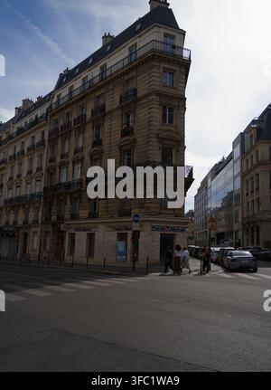 Edificio residenziale angolare in stile Haussmann a Parigi con una filiale della banca Crédit Mutuel al piano terra e pedoni che camminano Foto Stock