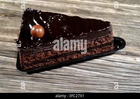Fetta di torta fudge ricoperta da una palla di cioccolato, una torta al cioccolato con consistenza, sapore o ricchezza che ricorda il fudge, una torta aromatizzata con mel Foto Stock
