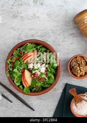 Insalata fresca di rucola con mele, noci, formaggio feta e semi di melograno servita in una ciotola rustica Foto Stock