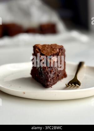 Prima vista di una fetta di torta al cioccolato umida servita su un piatto bianco con forchetta Foto Stock