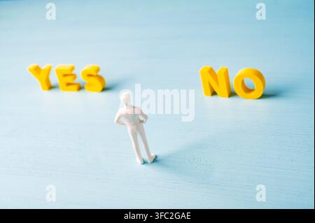 Concetto di presa di decisione con una figura di uomo d'affari in piedi tra le lettere GIALLO SÌ e NO. Simbolo di scelta, dilemma, incertezza, valutazione, al Foto Stock