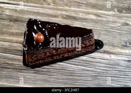 Fetta di torta fudge ricoperta da una palla di cioccolato, una torta al cioccolato con consistenza, sapore o ricchezza che ricorda il fudge, una torta aromatizzata con mel Foto Stock