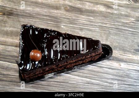Fetta di torta fudge ricoperta da una palla di cioccolato, una torta al cioccolato con consistenza, sapore o ricchezza che ricorda il fudge, una torta aromatizzata con mel Foto Stock