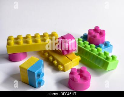 Blocchi da costruzione in plastica colorati sparsi su sfondo bianco, messa a fuoco selettiva Foto Stock
