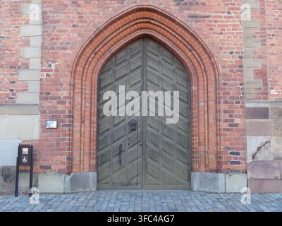 Una impressionante grande porta d'ingresso in legno ad arco con un'arco decorativo in mattoni su un edificio storico a Stoccolma. Foto Stock