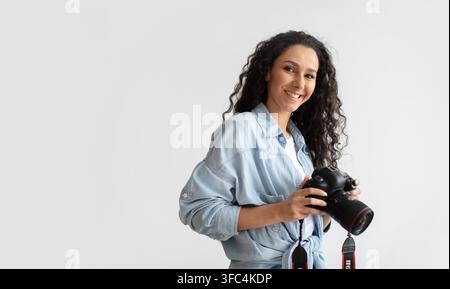 Donna sorridente che tiene una fotocamera in studio, concetto di fotografia ritratto Foto Stock